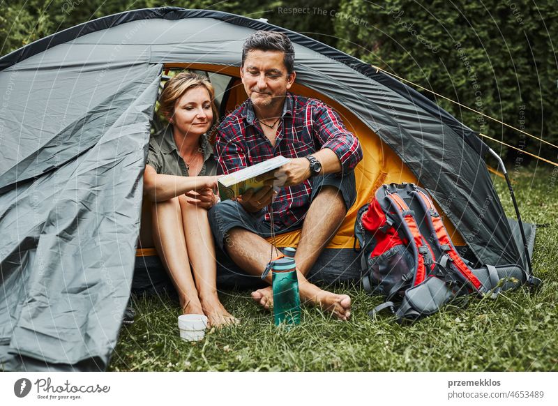 Glückliches Paar entspannt sich im Zelt beim Camping im Sommerurlaub. Mann und Frau planen nächste Reise mit Blick auf die Karte. Aktiv verbringen Urlaub im Freien in der Nähe der Natur