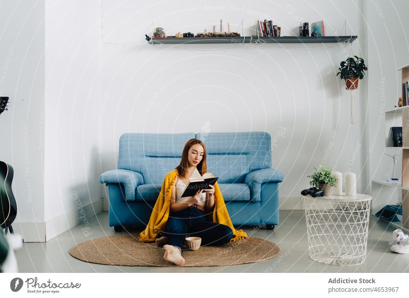 Konzentrierte Frau liest zu Hause ein Buch lesen sich[Akk] entspannen Freizeit Hobby Literatur Roman Wochenende ruhen Etage Zeitvertreib Komfort jung Kälte