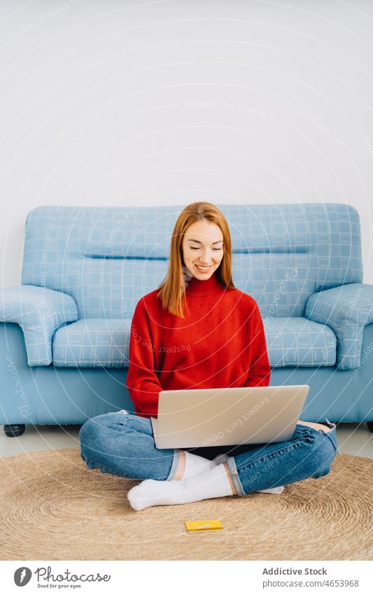 Fröhliche Frau mit Laptop zu Hause benutzend freiberuflich online Internet Freizeit abgelegen Arbeit Browsen Tippen Surfen Netbook Beine gekreuzt Wohnzimmer