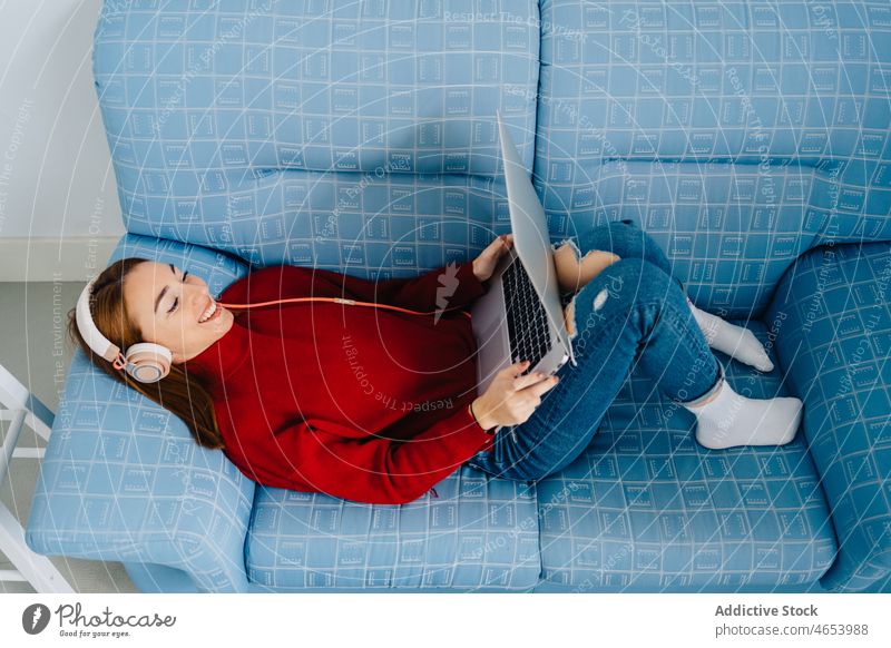Entspannte Frau mit Laptop und Kopfhörern benutzend online zu Hause Internet sich[Akk] entspannen Wochenende Freizeit Browsen zuschauen ruhen Surfen Netbook