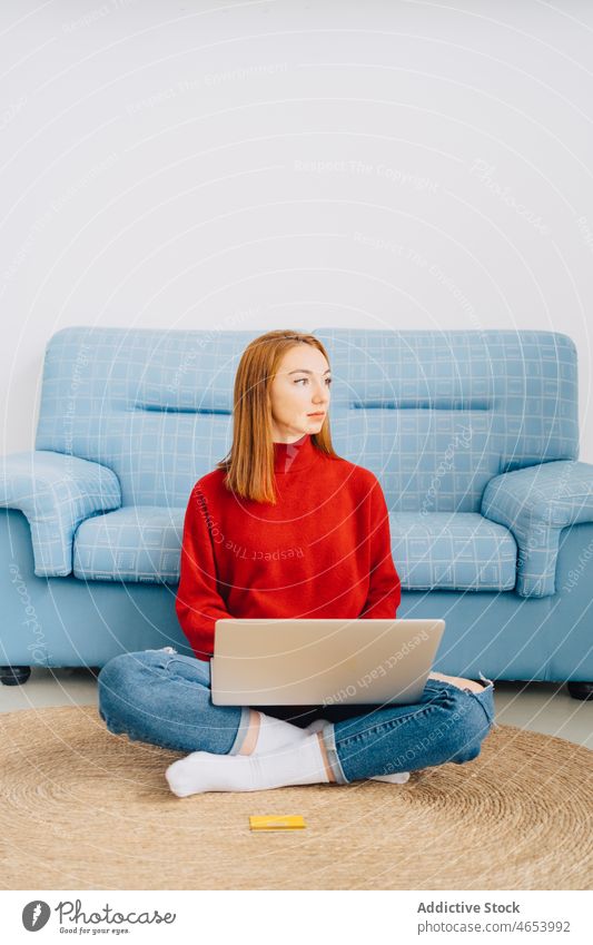 Frau benutzt Laptop zu Hause benutzend freiberuflich online Internet Freizeit abgelegen Arbeit Browsen Tippen Surfen Netbook Beine gekreuzt Wohnzimmer Sofa