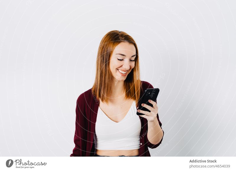 Lächelnde rothaarige Frau mit Mobiltelefon Smartphone benutzend Browsen online Internet Rotschopf Anschluss soziale Netzwerke Funktelefon Ingwer heiter Glück