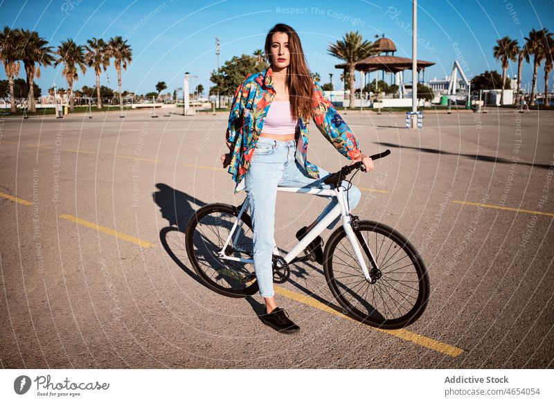 Frau fährt Fahrrad auf dem Bürgersteig Park Aktivität Sommer Wochenende Hobby Mitfahrgelegenheit Freizeit sorgenfrei jung Blauer Himmel genießen Straße Bäume