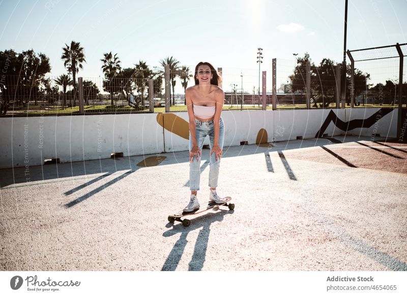 Junge lächelnde Frau fährt Longboard im Park Skater Skateplatz Hobby Aktivität Lächeln Großstadt urban Straße Sommer Mitfahrgelegenheit Glück schlank Fokus