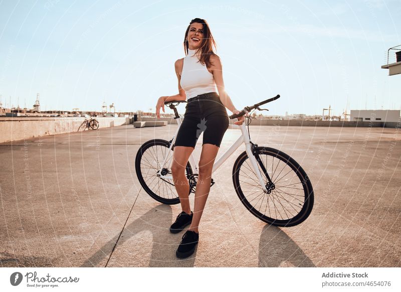 Lächelnde Frau fährt Fahrrad auf dem Bürgersteig Park Aktivität Sommer Wochenende Hobby Mitfahrgelegenheit Freizeit heiter sorgenfrei jung genießen Straße Glück
