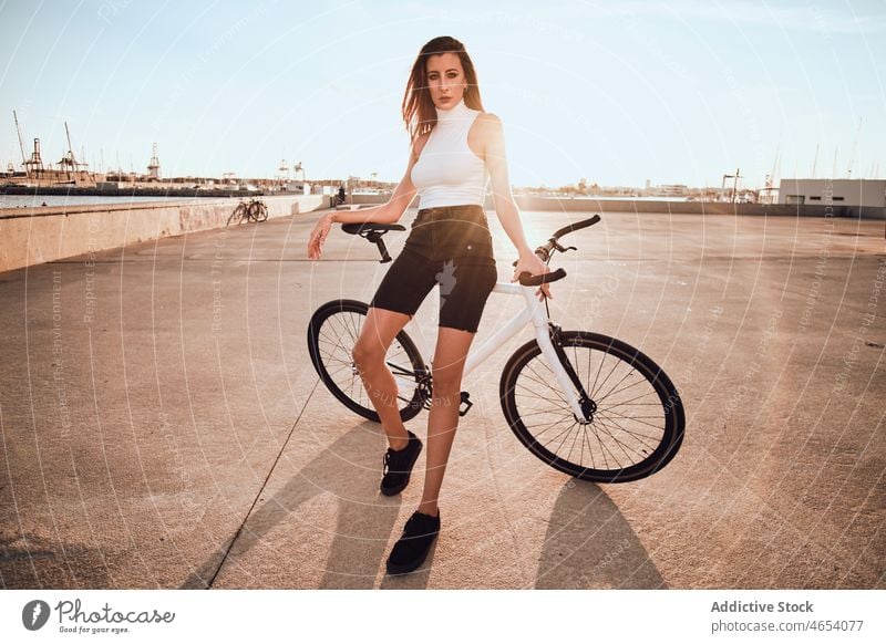 Frau fährt Fahrrad auf dem Bürgersteig Park Aktivität Sommer Wochenende Hobby Mitfahrgelegenheit Freizeit sorgenfrei jung Blauer Himmel genießen Straße