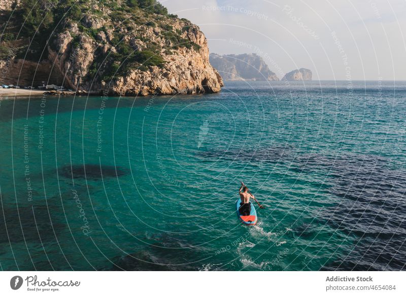 Mann übt Paddelsurfen auf einem Paddelbrett mit Ruder im Meerwasser Surfer Freiheit Surfen Zusatzplatine SUP Aktivität Brandung MEER klöppeln Surfbrett Wasser