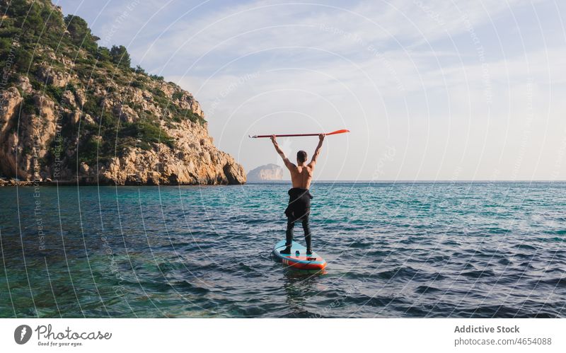 Mann übt Paddelsurfen auf einem Paddelbrett mit Ruder im Meerwasser Surfer Freiheit Surfen Gleichgewicht Zusatzplatine SUP Aktivität Brandung MEER Surfbrett