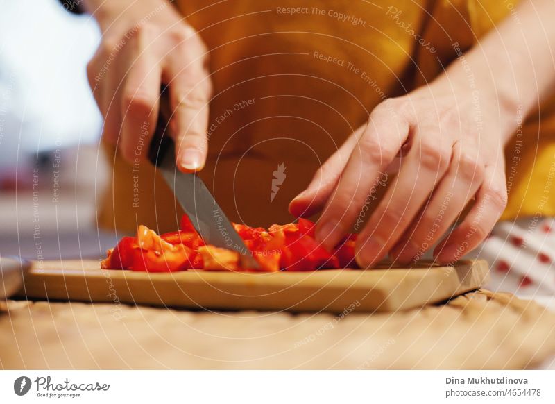 Frau hackt rote Paprika auf hölzernen Schneidebrett, Kochen gesundes Essen für das Abendessen. Koch macht Salat aus frischem Gemüse. Lebensmittel Küche Tomate