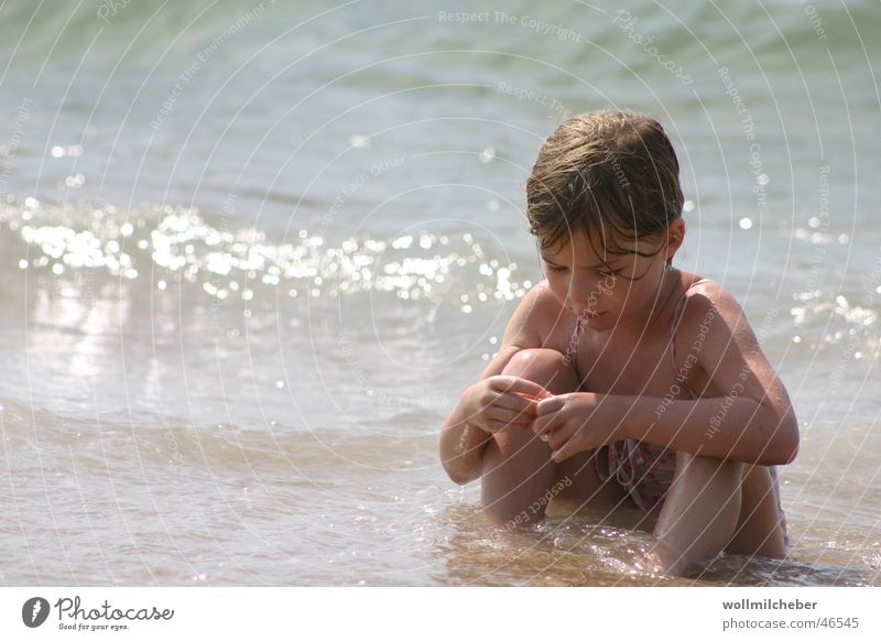 Strandnixe Meer Wellen Brandung Kind Spielen Muschel Mädchen verträumt vertiefen Außenaufnahme Ferne Wasser Sonne Konzentration Vor hellem Hintergrund tele
