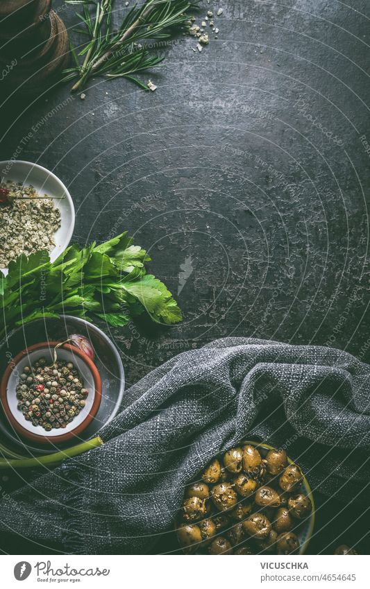 Lebensmittelhintergrund mit Schalen mit Oliven, Kräutern und Pfeffer Schüsseln Küchenkräuter Paprika dunkel Tisch Küchenhandtücher Essen zubereiten Vorbereitung