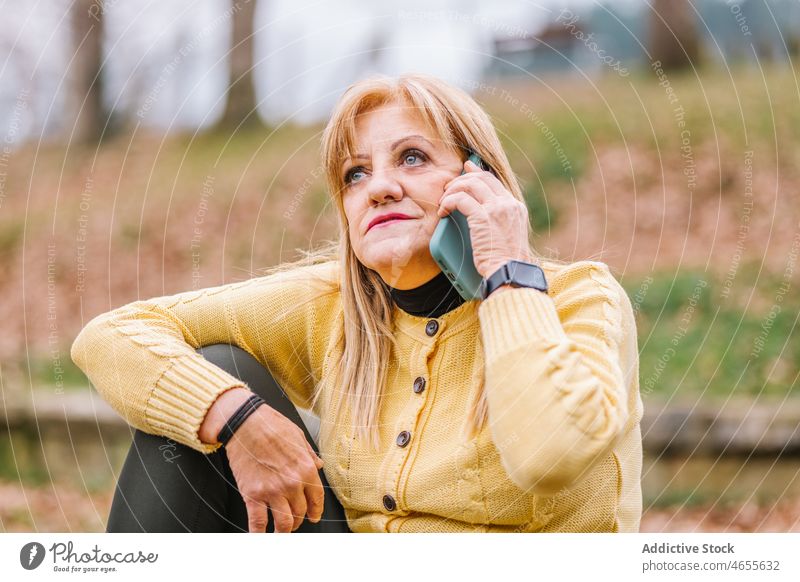 Ältere Frau spricht mit Smartphone im Park reden online Internet Lebensmitte Anschluss Vorschein feminin Stil Umwelt Bekleidung reif Erwachsener Herbst fallen