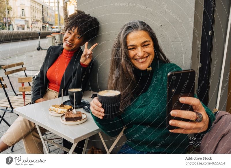 Hispanische Frau macht Selfie mit schwarzem Freund im Cafe Frauen Lachen benutzend Smartphone Kaffee Latte gestikulieren Frieden Glück Moment positiv