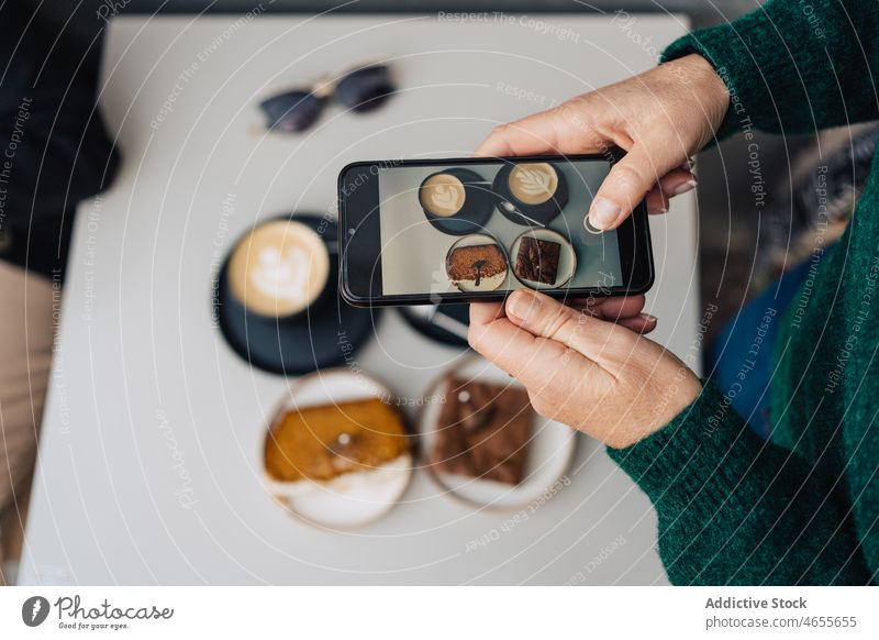 Frau filmt Dessert mit Milchkaffee auf dem Smartphone Blogger benutzend Kuchen Aufzeichnen Video Latte Sitzung soziale Netzwerke Latte Art Apparatur Gerät
