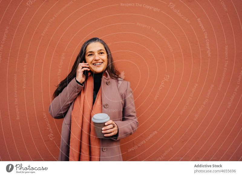 Zufriedene Dame spricht mit dem Handy Frau Smartphone Funktelefon Telefonanruf Gespräch Imbissbude Kaffee benutzend sprechen Lächeln zum Mitnehmen Erwachsener