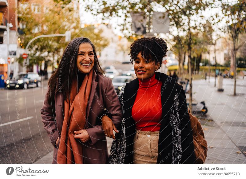 Lächelnde Frauen auf einer Straße in der Stadt Fußgänger Freund Großstadt Zusammensein froh Straßenrand urban Straßenbelag Arbeitsweg multiethnisch Freude Glück