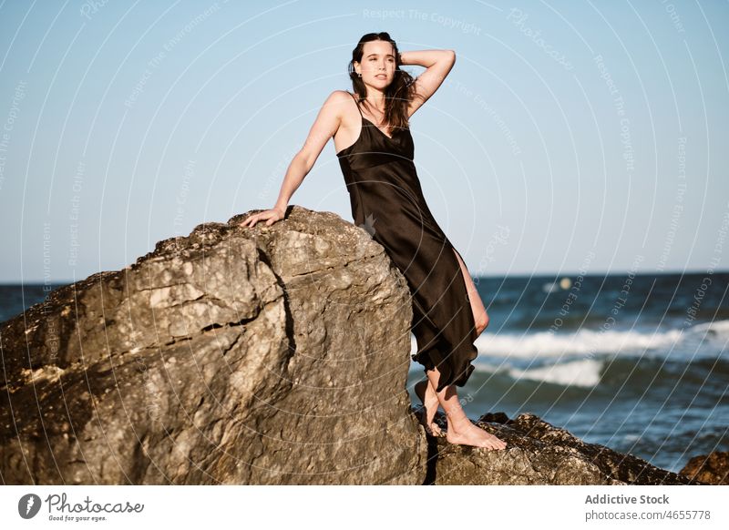 Stilvolle junge Frau lehnt an einem Stein am Meeresufer Felsen Kleid sinnlich Sommer felsig Urlaub Ufer Küste Wasser MEER nass Erholung Formation Seeküste Natur