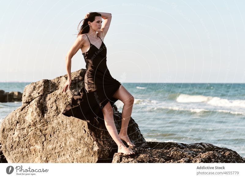 Stilvolle junge Frau lehnt an einem Stein am Meeresufer Felsen Kleid sinnlich Sommer felsig Urlaub Ufer Küste Wasser MEER nass Erholung Formation Seeküste Natur
