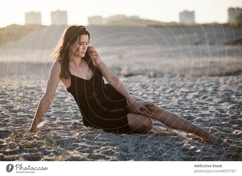 Schlanke attraktive Frau sitzt auf Sandstrand in sonnigen Tag wüst Sommer wolkenlos Blauer Himmel Barfuß Sonne Kleid Harmonie Sonnenkleid tagsüber Strand reisen