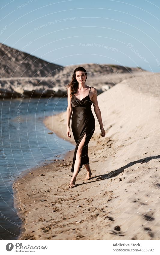 Schlanke attraktive Frau steht am Sandstrand in sonnigen Tag wüst Sommer wolkenlos Meeresufer Blauer Himmel Barfuß Seeküste Sonne Kleid Harmonie Sonnenkleid