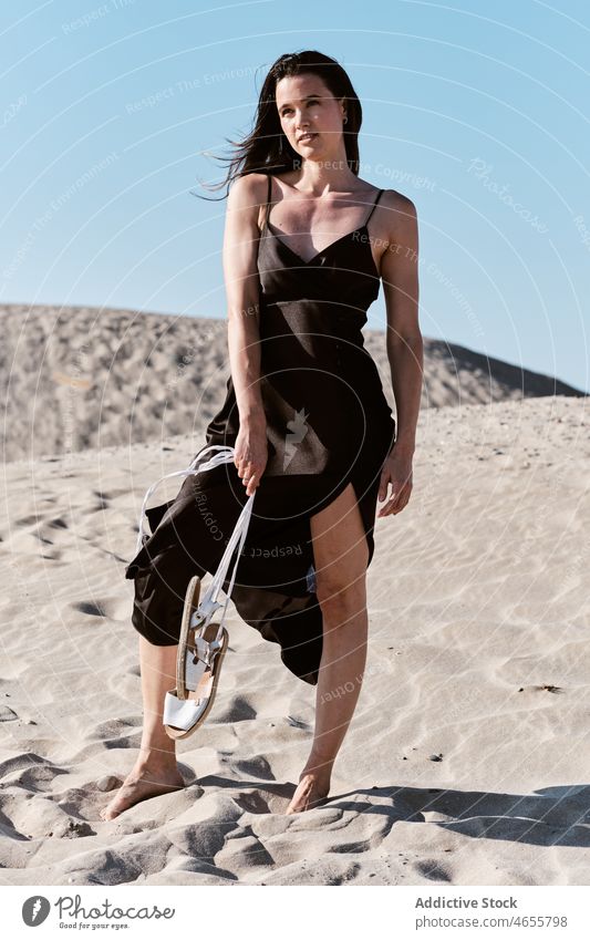 Schlanke attraktive Frau steht am Sandstrand in sonnigen Tag wüst Sommer wolkenlos Blauer Himmel Barfuß Sonne Kleid Harmonie Sonnenkleid tagsüber Strand reisen