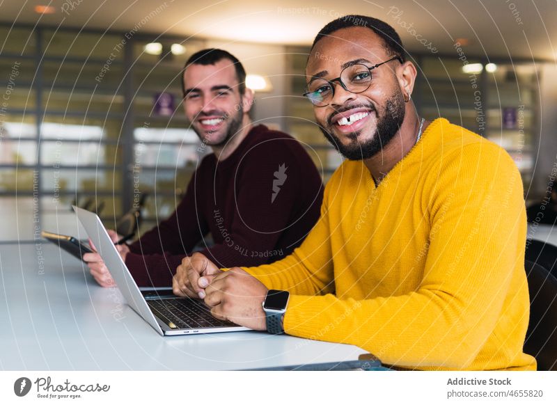 Positiv gestimmte Männer mit Laptop und Tablet in einem modernen Arbeitsbereich Kollege Partner Mitarbeiterin zusammenarbeiten Tisch Teamwork Arbeitsplatz