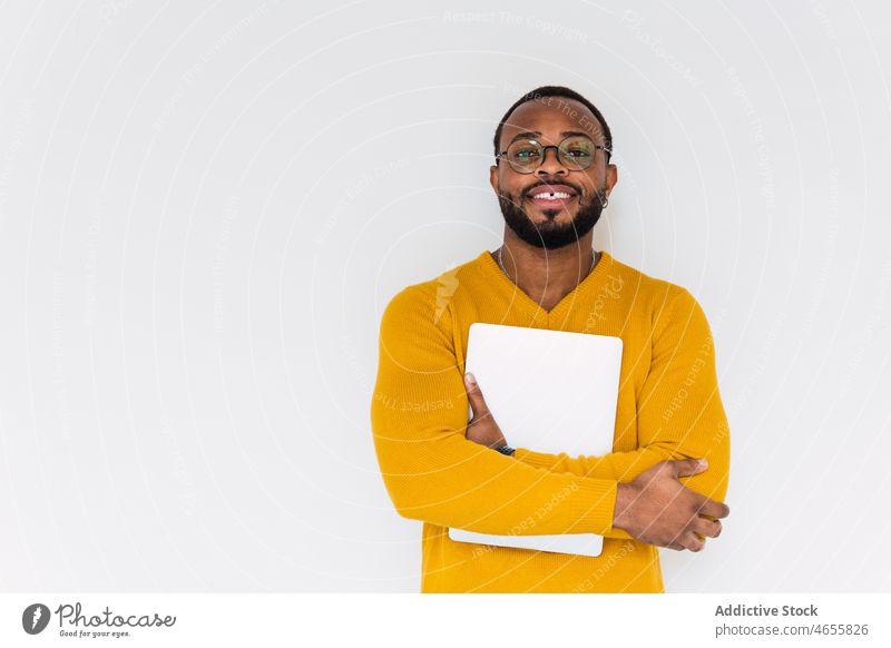 Lächelnder schwarzer Mann mit Laptop Netbook freiberuflich Individualität Gerät benutzend Arbeiter Mitarbeiter online männlich Afroamerikaner positiv Zahnlücke