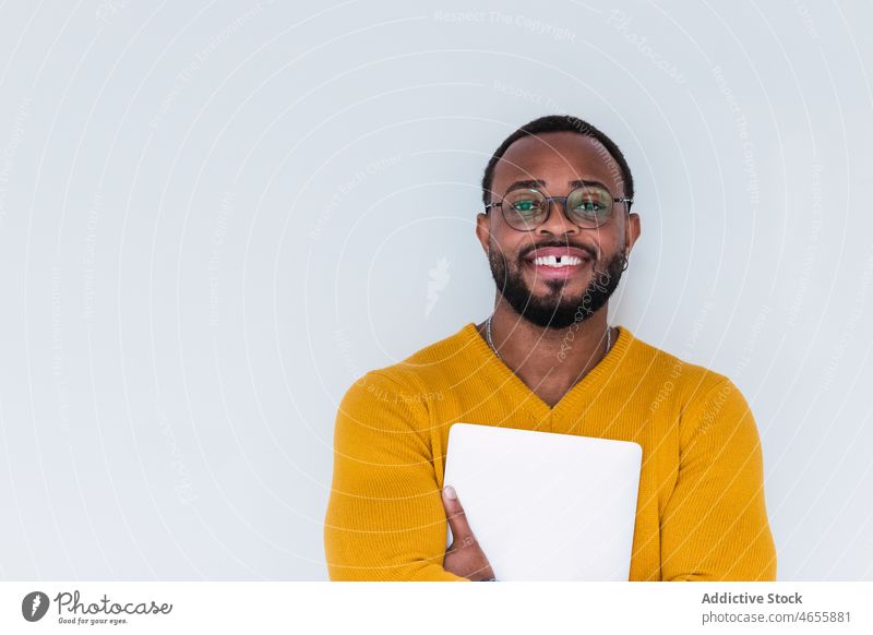 Lächelnder schwarzer Mann mit Laptop Netbook freiberuflich Individualität Gerät benutzend Arbeiter Mitarbeiter online männlich Afroamerikaner positiv Zahnlücke