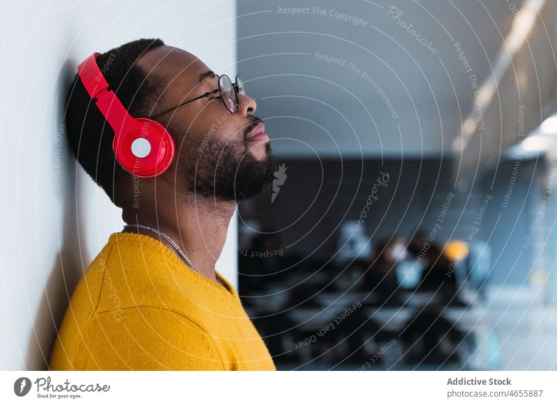 Schwarzer Mann, der mit Kopfhörern Musik hört benutzend zuhören sich[Akk] entspannen ruhen Kälte Gesang meloman männlich schwarz Afroamerikaner genießen Gerät