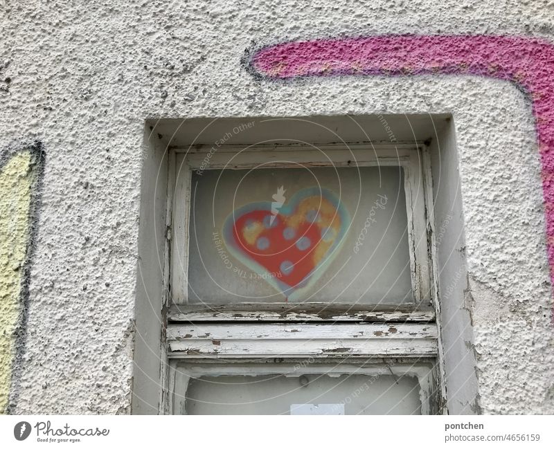 Auf ein altes Fenster eines industriegebäudes wurde ein Herz gesprayt. Graffiti. vandalismus jugendkultur fenster marode Fassade Außenaufnahme Menschenleer