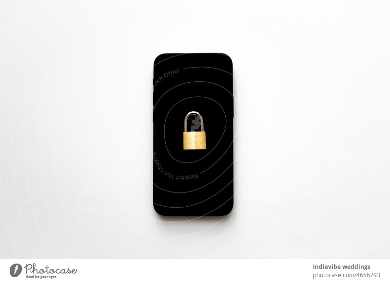 Ein isoliertes schwarzes Smartphone mit einem kleinen Vorhängeschloss darauf auf weißem Hintergrund. Telefonschutz Idee. Online-Datenschutz-Konzept. Schutz vor Cyber-Angriffen.