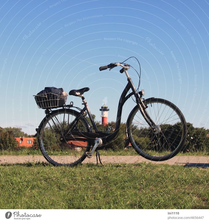 Fahrradpause auf dem Deich mit Blick auf den Leuchtturm Freizeit Urlaub Sommer schönes Wetter Insel Radweg Fahrradtour Radfahren Radständer Gepäck Fahrradkorb
