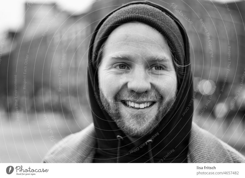 SCHWARZWEISS - FRÖHLICH - LACHEN Schwarzweißfoto Porträt Mann Bart 30-35 Jahre Junger Mann Lächeln Wegsehen Schwache Tiefenschärfe Außenaufnahme Erwachsene