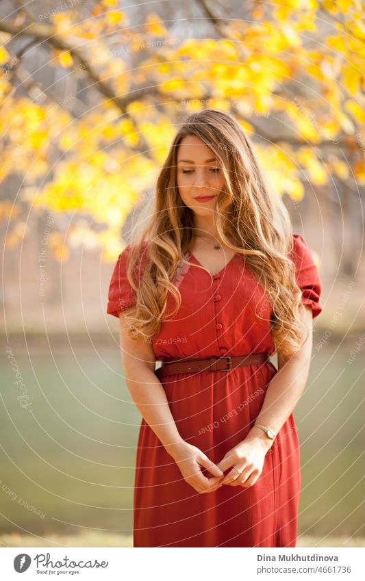 schöne Frau mit langen in rotem Kleid zu Fuß in den Wald am See unter Bäumen. Romantischer Spaziergang im Wald im Herbst Natur auf Herbstblätter. Erwachsener