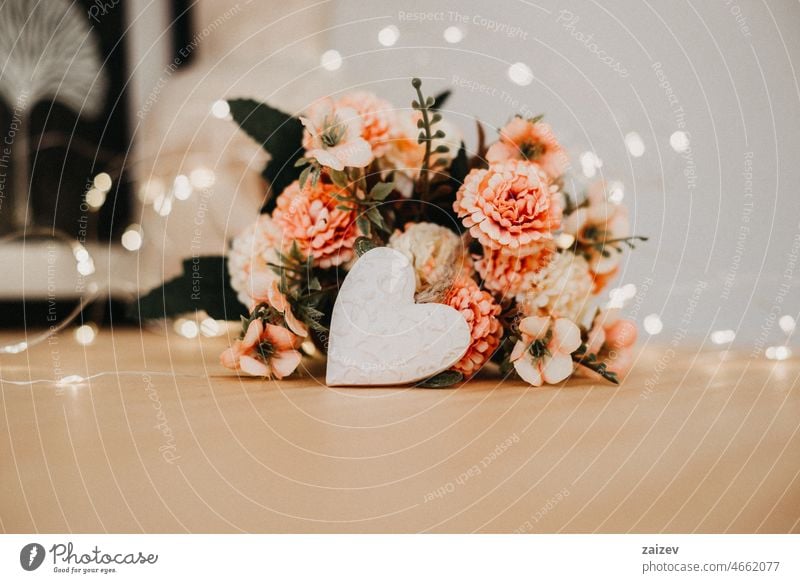 Holztisch mit einem Blumenstrauß und einem weißen Herz Tisch Textfreiraum Hintergrund geblümt Haufen niemand Bokeh Lichter Arbeitsbereich Tag schreibend Blüte