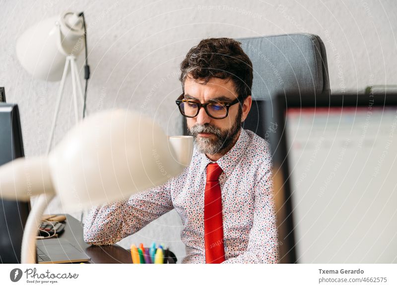 Geschäftsmann mittleren Alters mit Bart und Brille beim Kaffee im Büro Designer Atelier Vollbart Krawatte pc Computer Schreibtisch Dienststelle Kreativität