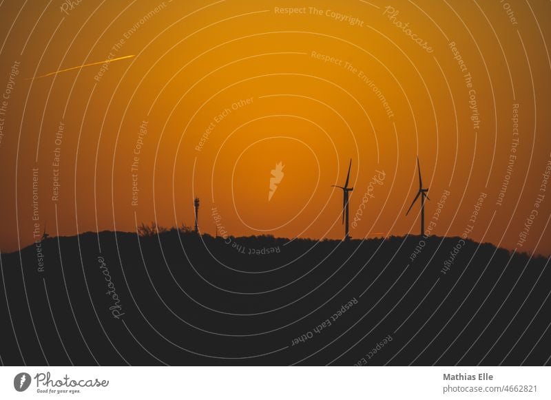 Energiegewinnung durch Windkraftanlagen im Sonnenaufgang ökostrom windkraftanlage windenergieanlage feld generator silhouette klimaschutz abend