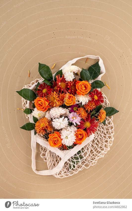 Orange und rote Gartenblumen in der Netztasche Mockup für Karte Hintergrund in natürlichen Erdtönen Rosen, Gänseblümchen, Chrysanthemen Blume sehr wenige