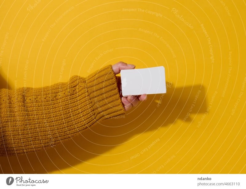 Weibliche Hand hält leere weiße Papier-Visitenkarte auf einem gelben Hintergrund. Kopierraum Anzeige Erwachsener inserieren Inserat Arme blanko Business