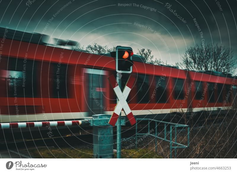 Der Zug fährt auch bei schlechtem Wetter Bahn Schienenverkehr Geschwindigkeit Gleise Eisenbahn Bahnfahren Bahnübergang Schranke geschlossen Signal rot
