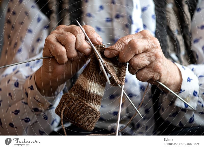 Nahaufnahme der Hände einer älteren Frau beim Stricken von Socken stricken Hand alt Oma Handwerk Lebensalter Senior Arthrose Krankheit Arthritis Finger Juckreiz