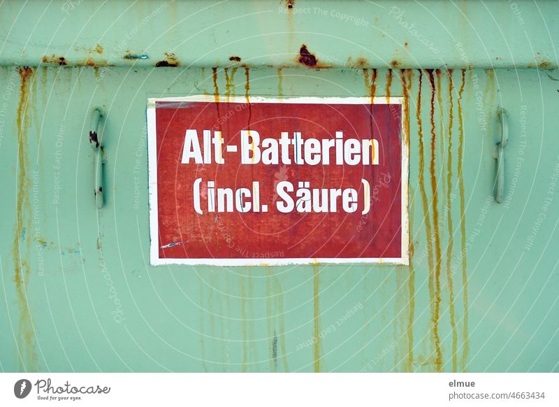 Alt-Batterien (incl. Säure) steht auf einem roten Schild an einem grünen Container mit Rostspuren durch Schwefelsäure Entsorgung Altbatterie Bleibatterie