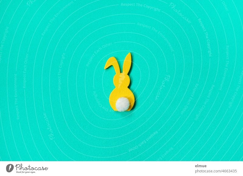 stilisierter gelber Hase mit weißer Blume und Knickohr auf cyanfarbenem Untergrund / Flatlay Osterhase Hase & Kaninchen Hasenohren Hinterteil Illustration