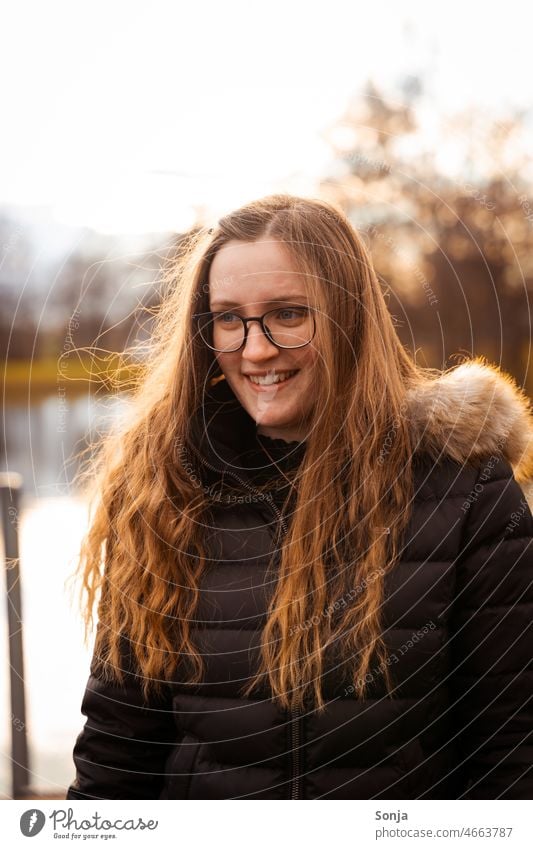Eine junge lächelde Frau mit Brille und langen Haaren. langhaarig Lächeln draußen Winter Porträt Mensch Erwachsene feminin Farbfoto Junge Frau Außenaufnahme