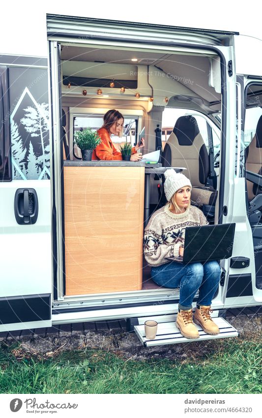 Frau bei Telearbeit in der Tür eines Wohnmobils sitzend Frauen Laptop Sitzen Kleintransporter Ausflug Tablette Fernarbeit Menschen Wohnwagen Denken meditierend
