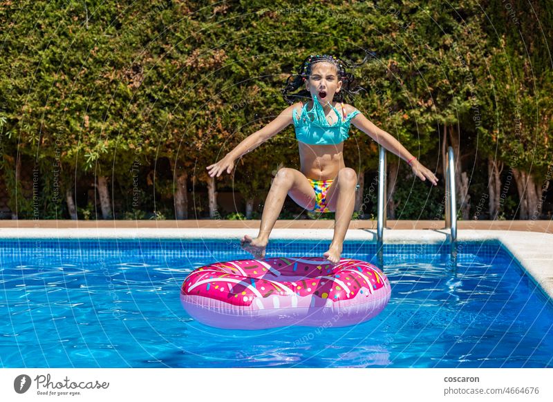 Kleines Mädchen springt auf einem Gummiring in ein Schwimmbecken Aktivität schön Bikini Boje Kind Kindheit Kinder Sinkflug Krapfen Doughnut Schwimmer Spaß