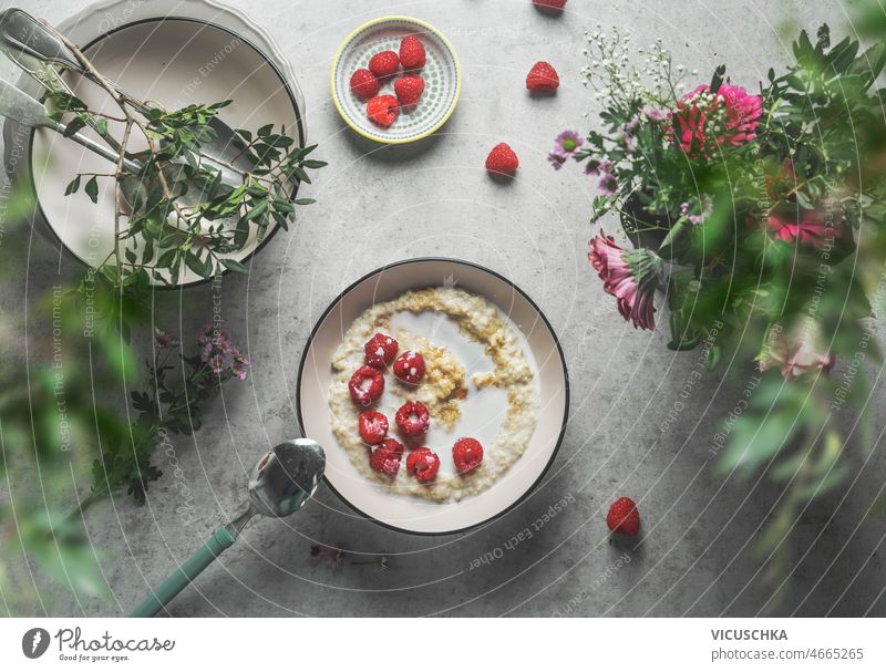 Hausgemachte Porridge-Schale mit Milch-Himbeeren am grauen Beton-Küchentisch selbstgemacht Haferbrei Schalen & Schüsseln melken Besteck schön Sommer Blumen