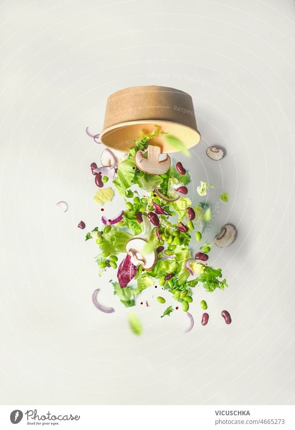 Gesunder grüner Salat fällt aus nachhaltiger Schüssel auf weißem Wandhintergrund Gesundheit Salatbeilage fallend Schalen & Schüsseln bei Weiß Hintergrund