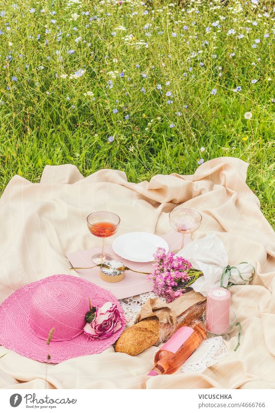 Sommerpicknick mit Wein, Käse, Baguette, rosa Sonnenhut, Blumen und Kerze auf beiger Decke Picknick Wiese romantisch Termin & Datum Idee Lebensmittel trinken