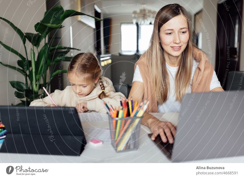 Weiße Familie arbeitet und lernt online zu Hause und mit Laptop. Fernunterricht oder Fernstudium für Kinder. Hübsche, elegante Schülerin, die während der Coronavirus-Covid-19-Quarantäne und der sozialen Distanzierung Hausaufgaben in Mathematik macht